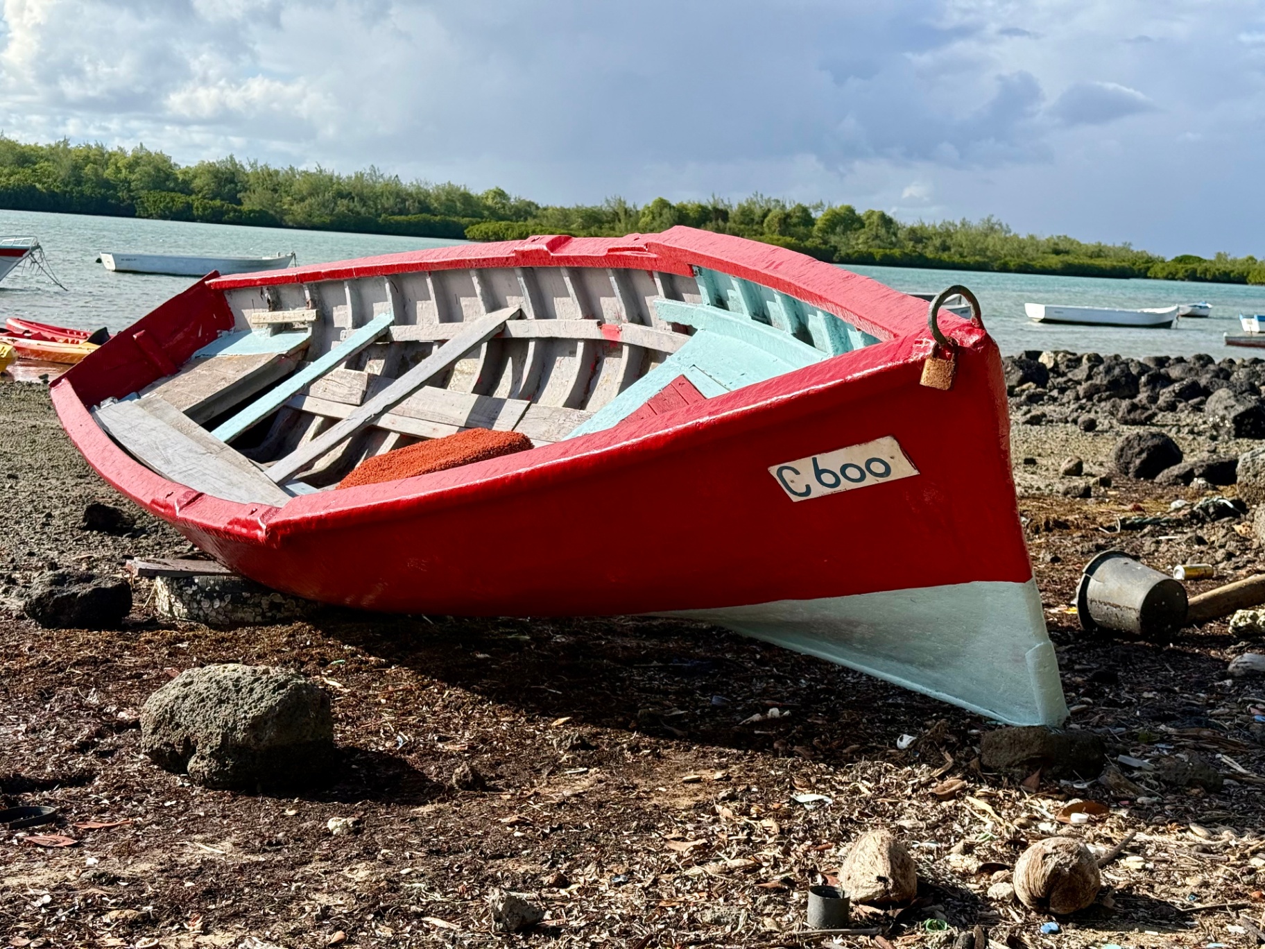 A traditional red Mauritian fishing boat resting on the shore